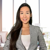 a young woman in a blazer standing in front of a desk